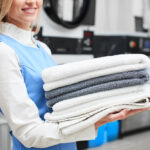 Worker,Laundry,Girl,Holding,Fresh,Towels,In,Her,Hands,And